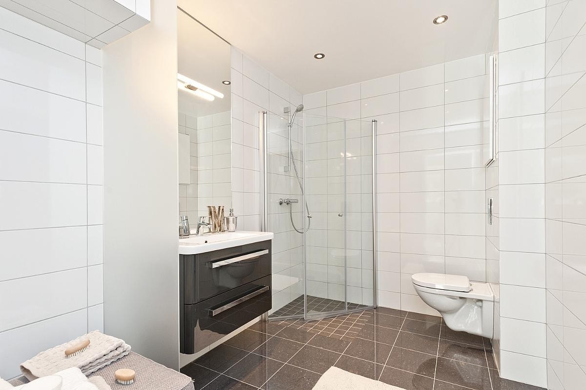 Bad med dusjhjørne, klosett og opplegg til vaskemaskin Galleribilde