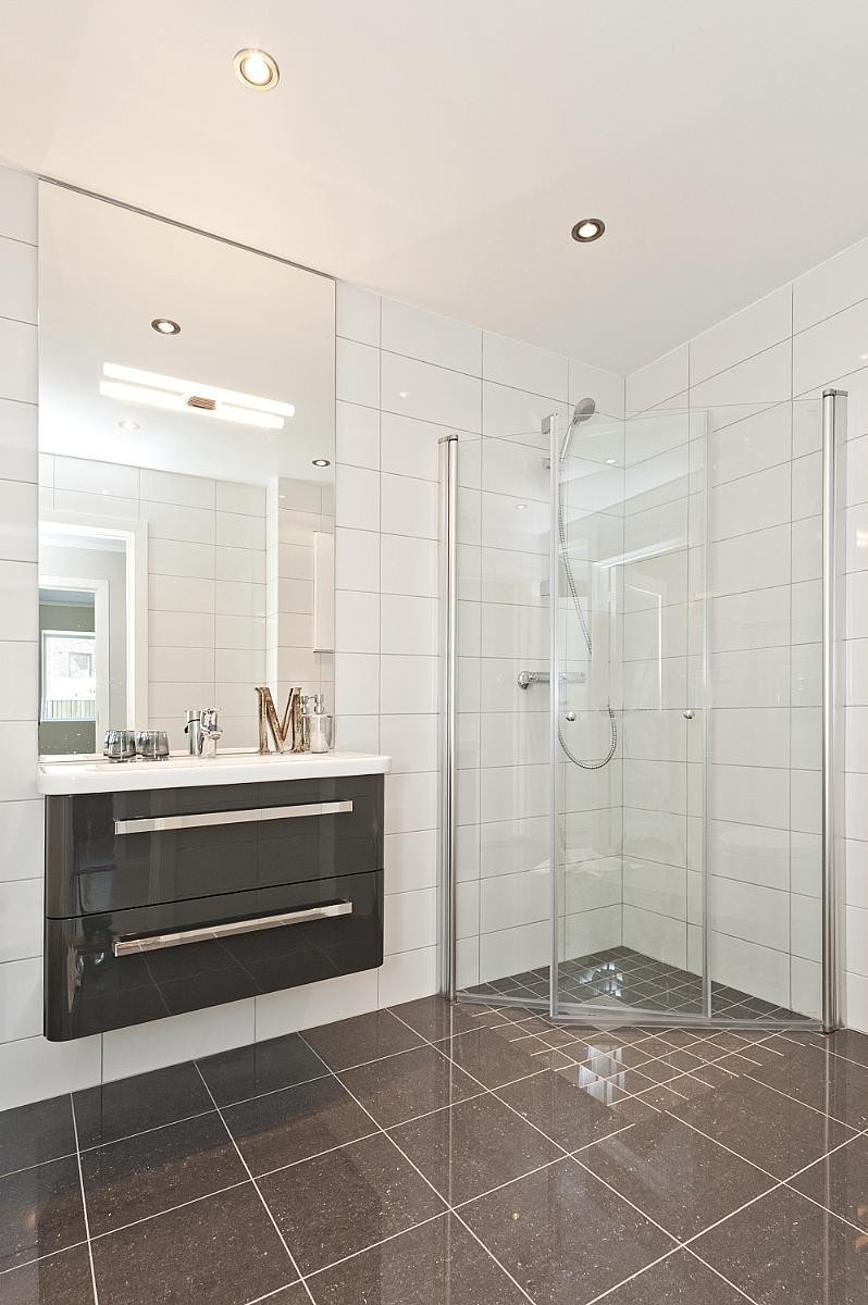 Bad med dusjhjørne, klosett og opplegg til vaskemaskin Galleribilde