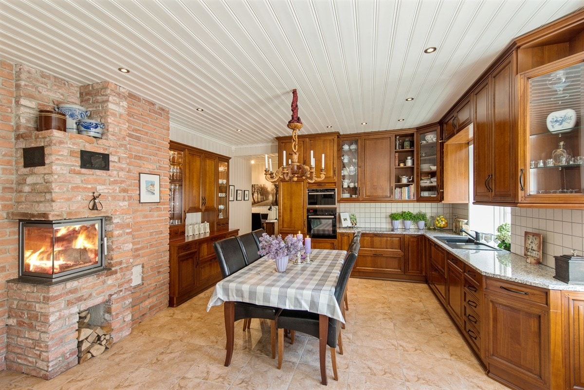 Kjøkken/allrom med plass for langbord og peis Galleribilde