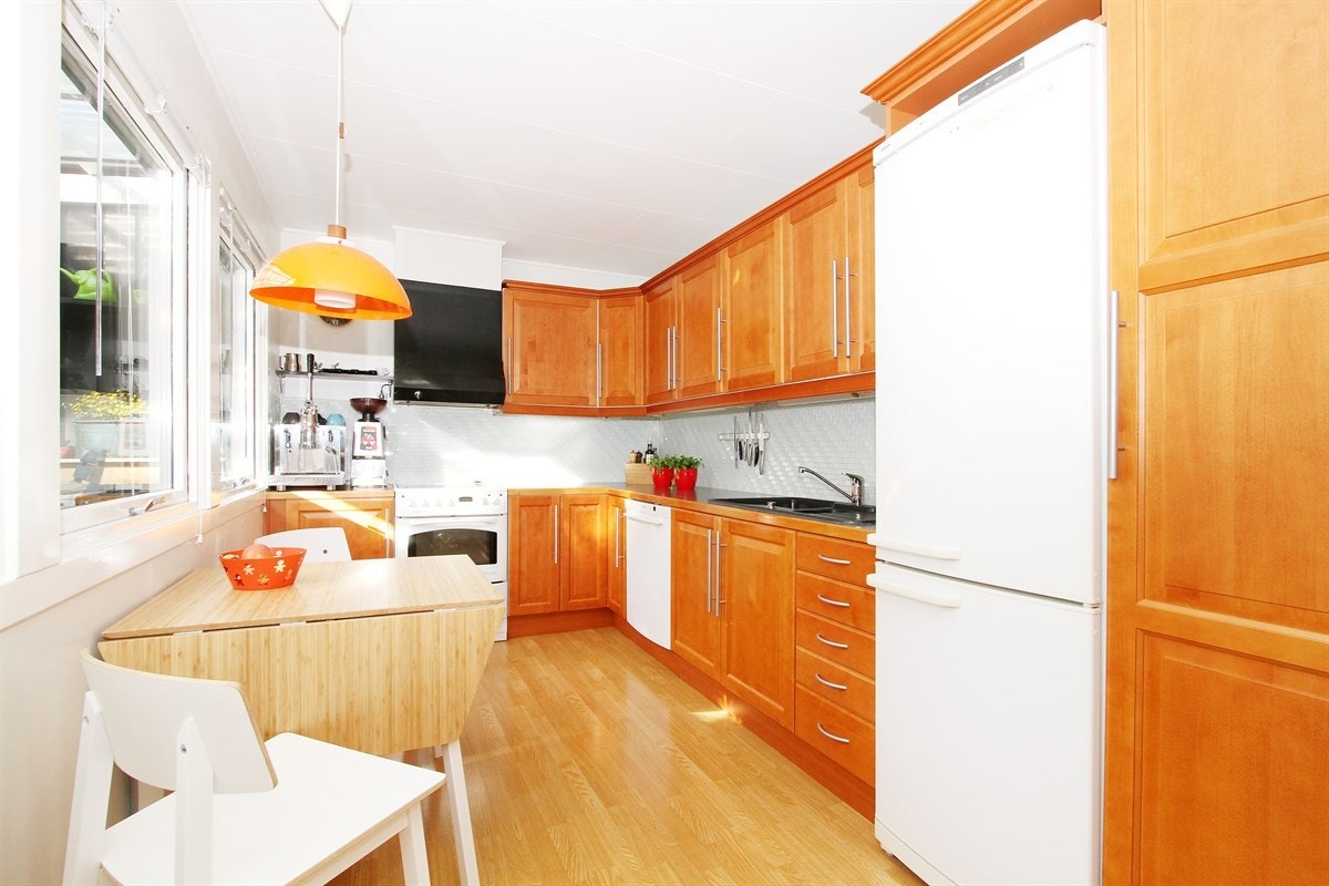 Kjøkkeninnredning med profilerte kirsebærfronter og laminat benkeplate med nyere fliser over Galleribilde