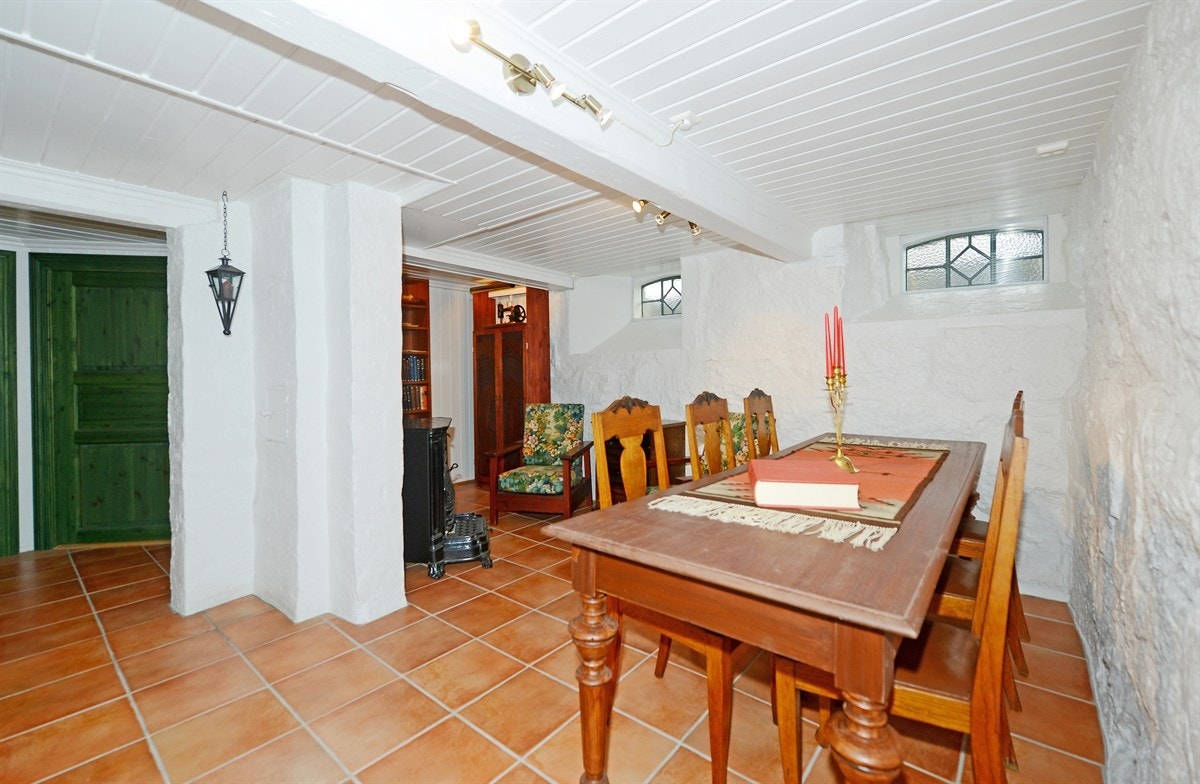 Kjellerstue på ca. 20 m² med flislagt gulv med varmekabel samt gammel peis/kamin. Galleribilde