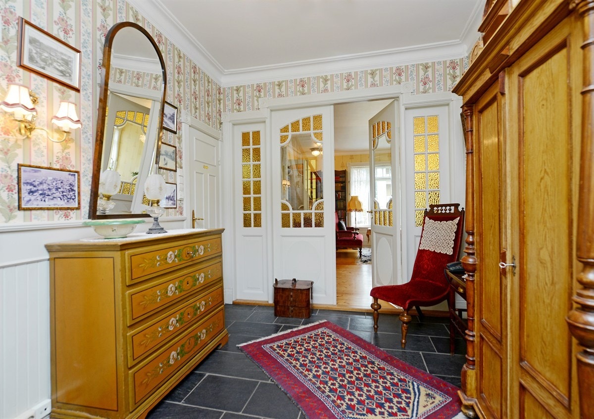 Hall med bred trapp til 2.etasje og nedgang til kjeller. Det er skifer, varmekabel og vannbåren varme på gulv. Det er høy 2 fløys, dør med slepet glass inn til stue. Galleribilde