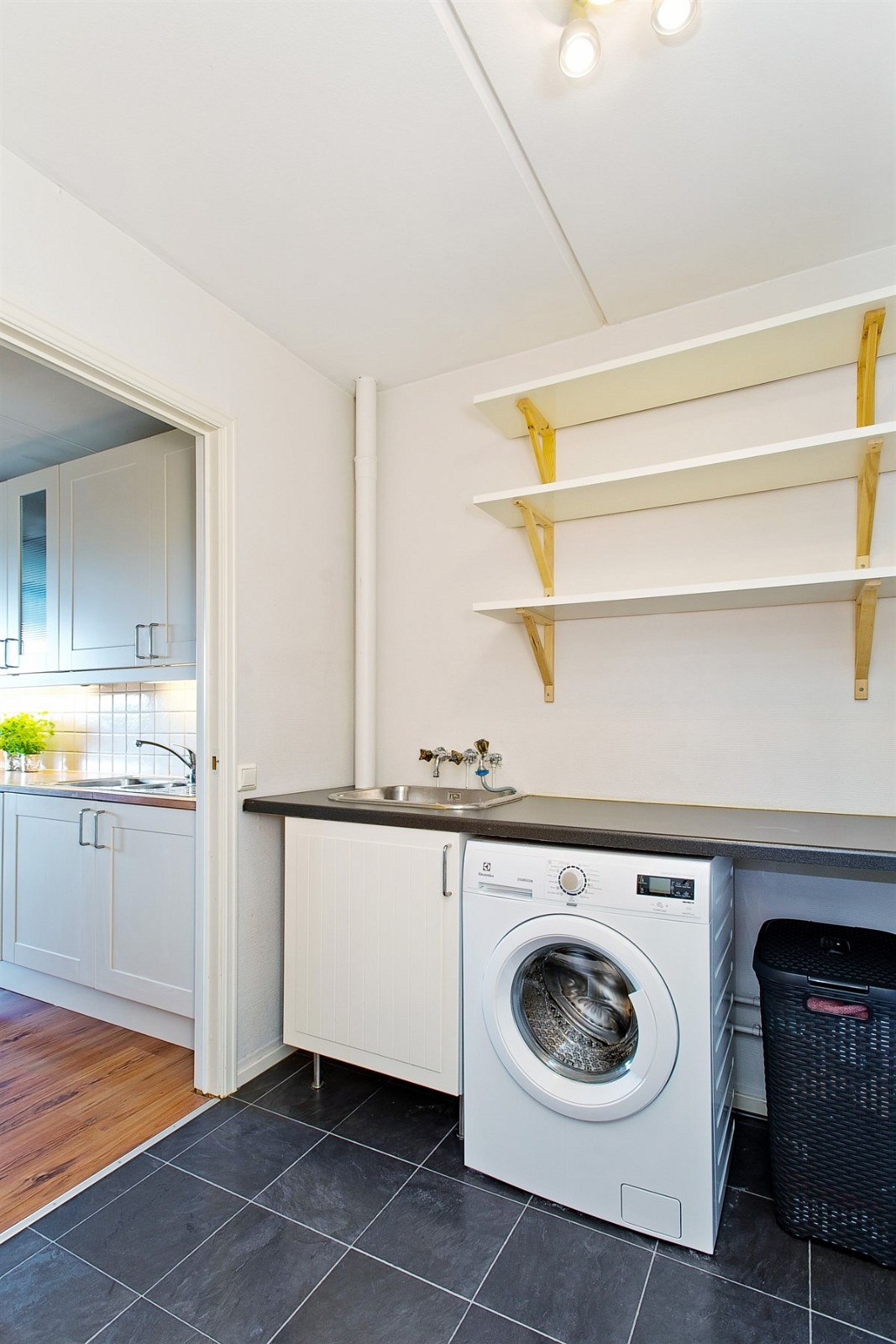 Separat vaskerom med praktisk benk med utslagsvask og hyller/skap for oppbevaring Galleribilde