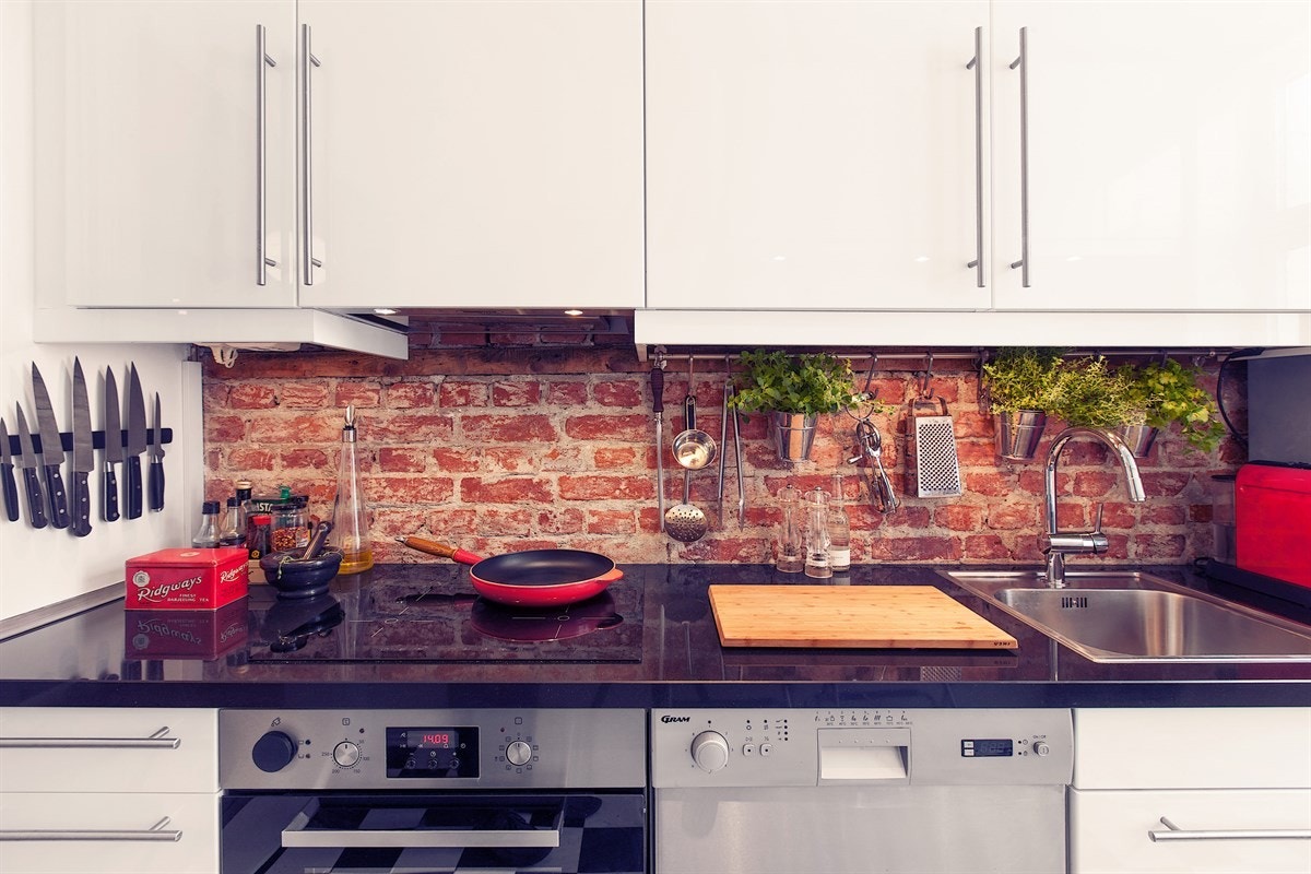 Benkeplaten i sort stein er en fin kontrast til de hvite høyglansfrontene, sjakkbrett-vinylen og teglstensveggen. Galleribilde