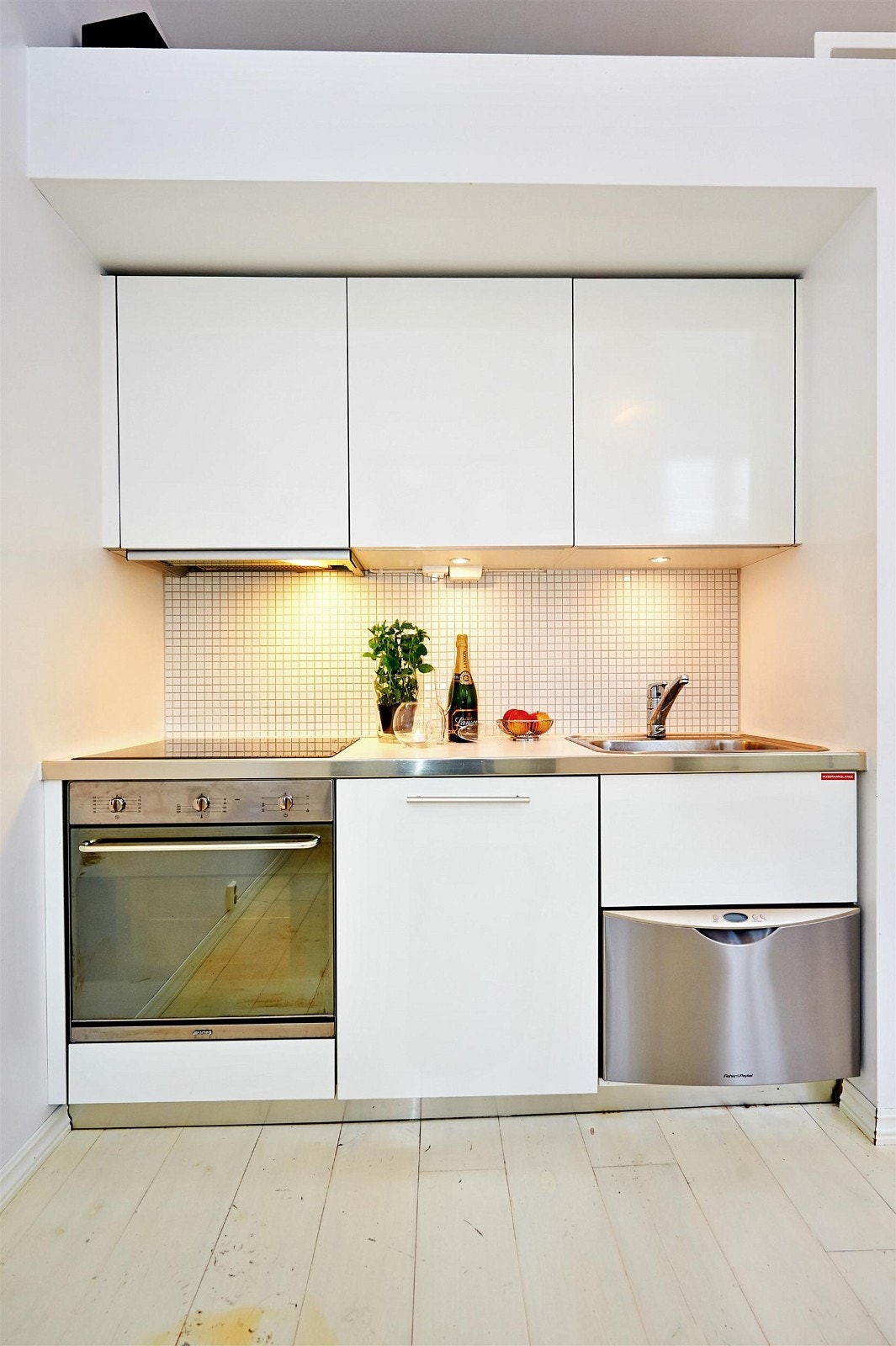 Lekkert åpent kjøkken med mosaikk fliser mellom overskap og benkeplate. Galleribilde