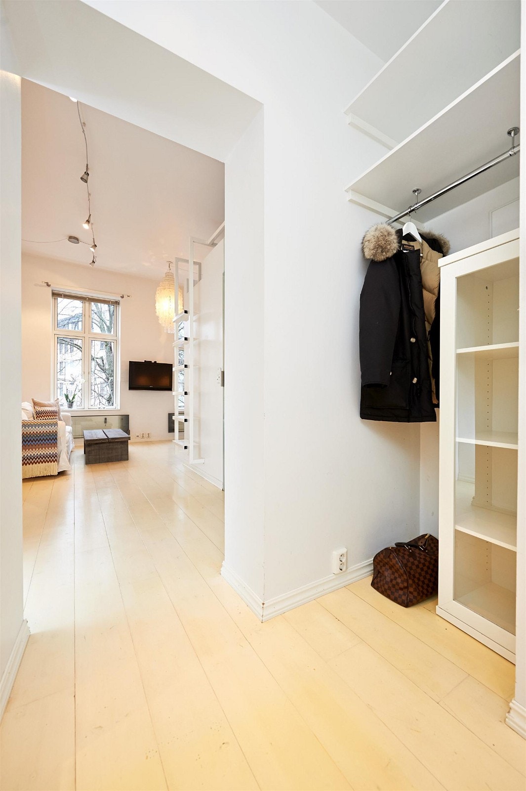 Leiligheten sett fra entreén med garderobeplass inn mot den lyse stuen. Galleribilde