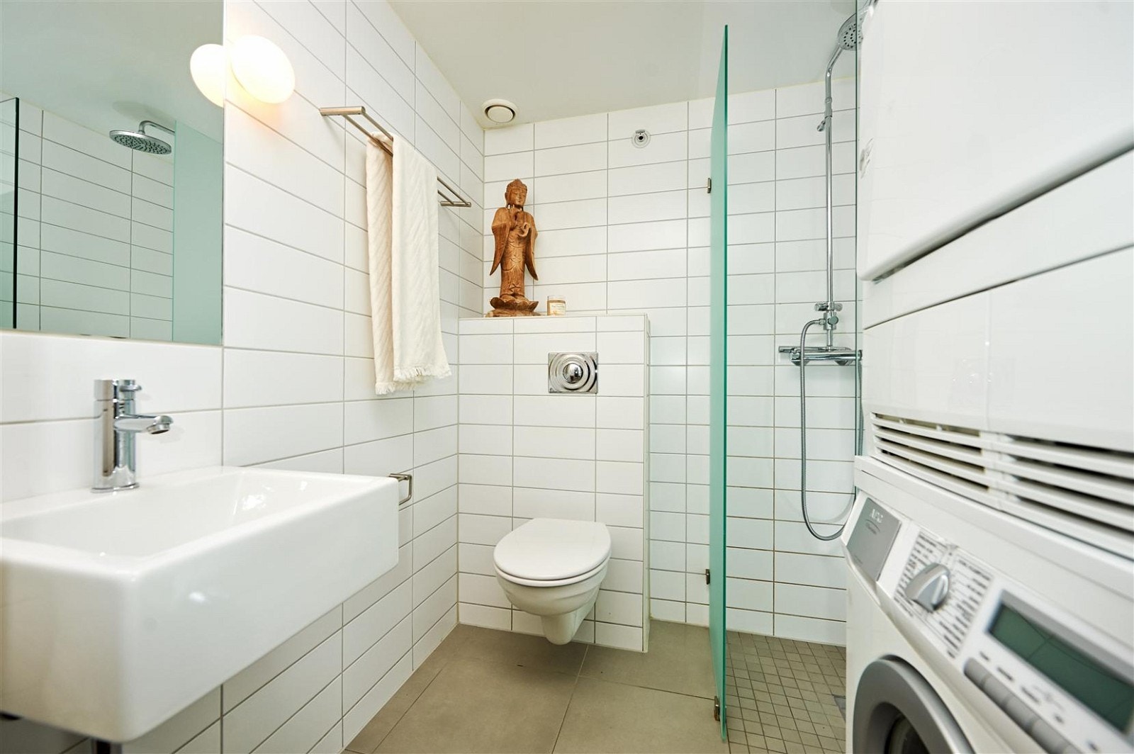 Lyst og pent bad med vegghengt wc, servant, innfelt speil. Dusjhjørne med dører i herdet glass.
Flislagt gulv med varmekabler. Opplegg for vaskemaskin. Galleribilde