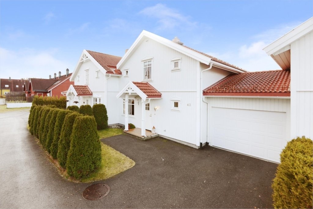 Fasade, inngangsparti. Tilhørende garasje vegg-i-vegg med boligen samt asfaltert gårdsplass. Galleribilde