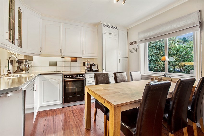 Kjøkken i 1. etasje med hvite profilerte fronter. Plass til spisebord på kjøkkenet. Galleribilde