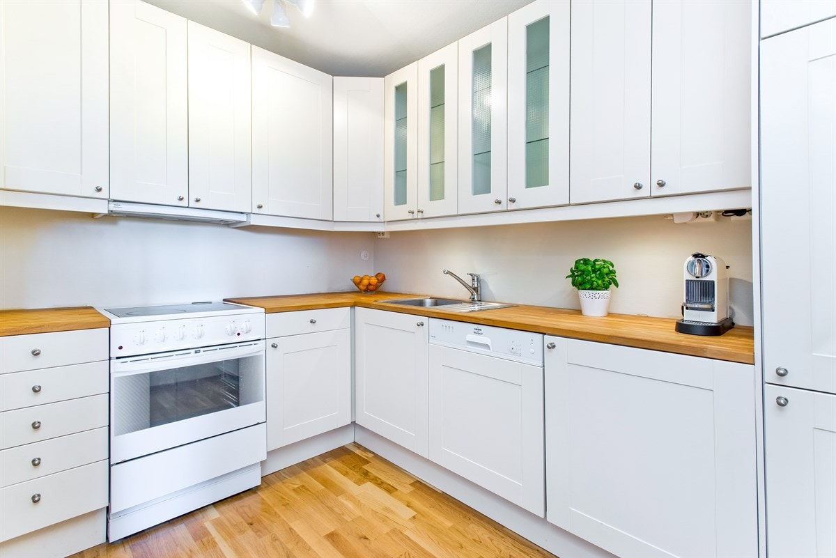 Lyst og pent kjøkken fra Ikea med integrert oppvaskmaskin, kjøl-/fryseskap og benkeplate i heltre Galleribilde