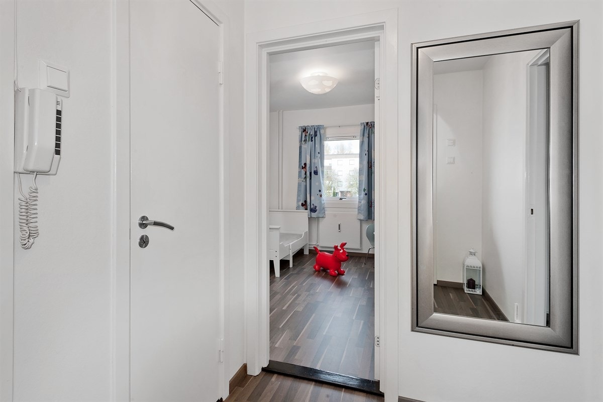 Entreen er innbydende med mørk laminat på gulv og lysmalte vegger. Rommet er praktisk innredet og har bl.a. åpen garderobeløsning. Entreen er holdt i en moderne stil som harmonerer bra med øvrige rommene i boligen. Galleribilde