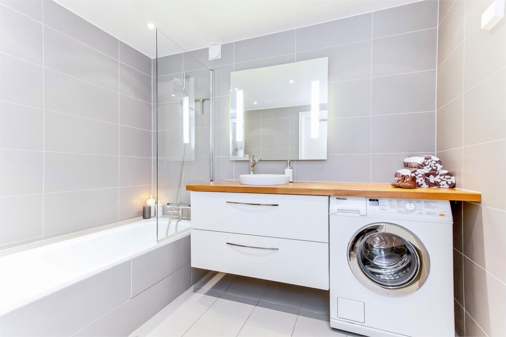 Badet har servant med et stilrent armatur, festet til en stor benkeplate. Opplegg til vaskemaskin. Galleribilde