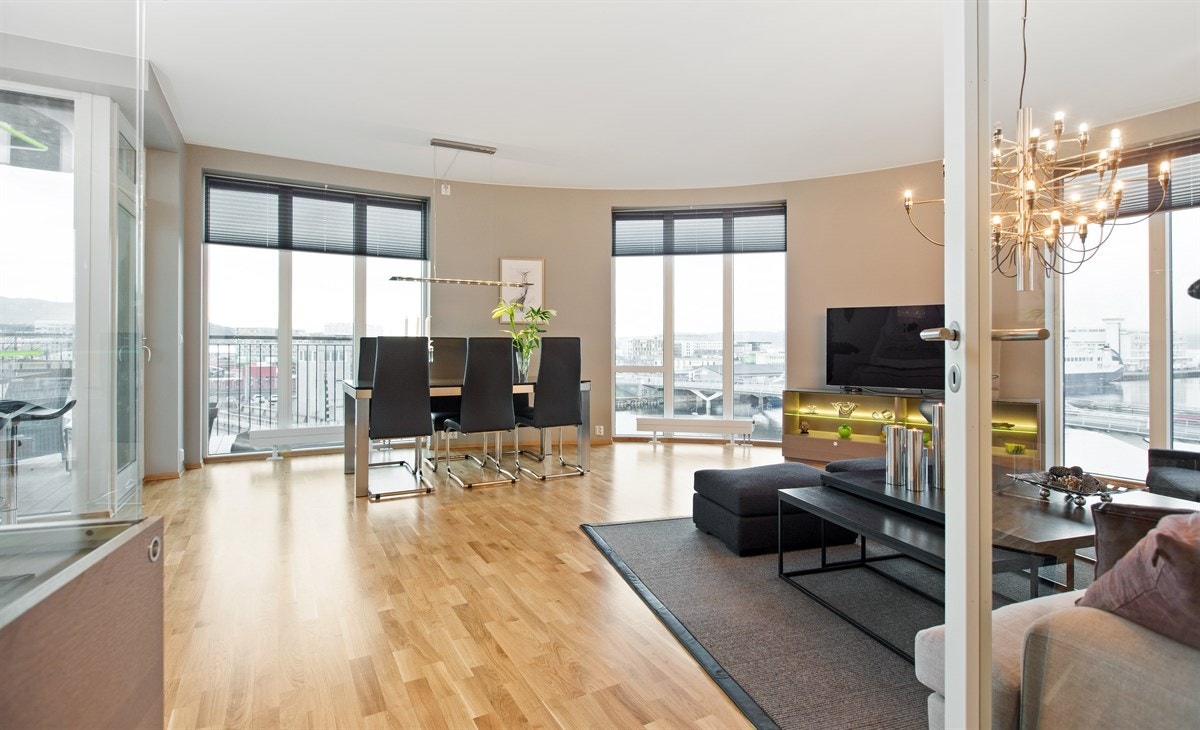 PROA Eiendomsmegling - Stuen har store vindusflater, og en buet utforming som gir rommet "prikken over i`en".
Det er montert teknisk plissegardin på alle vinduer som skjermer for sol og varme uten at det går på bekostning av utsikten. Galleribilde