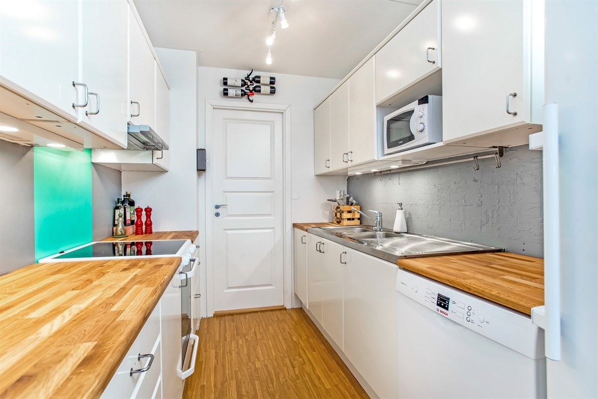 Hvitlaminert kjøkkeninnredning med heltre benkeplate. Inngang til vaskerom. Hvitevarer medfølger. Galleribilde