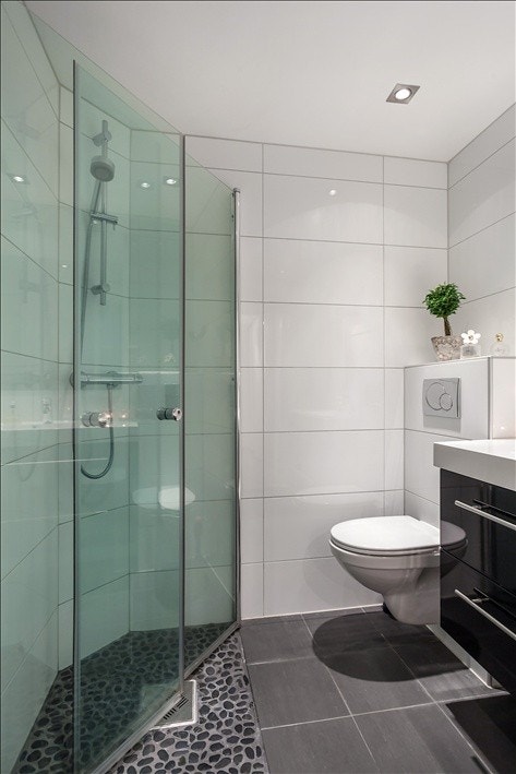 Svingbare glassdører i dusj, med rullestein på gulvet. Galleribilde