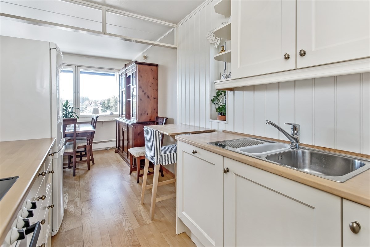 Lyst og hyggelig kjøkken i heltre med integrert ovn, koketopp og oppvaskmaskin Galleribilde