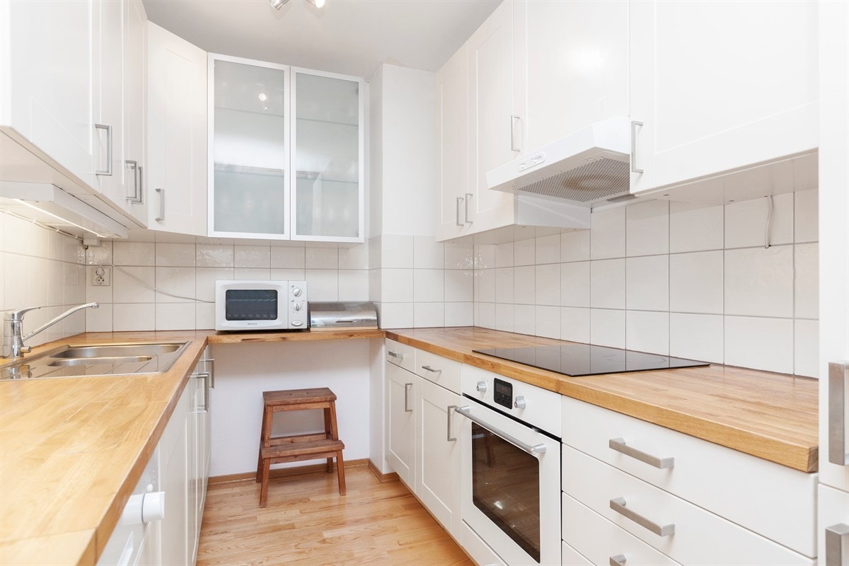 Pent hvitt kjøkken med integrerte hvitevarer. Galleribilde