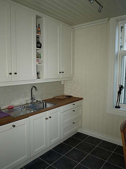 Del av høystandardkjøkkenet fra Huseby med integrert oppvaskmaskin. Utsikt til koselig bakgård. Galleribilde