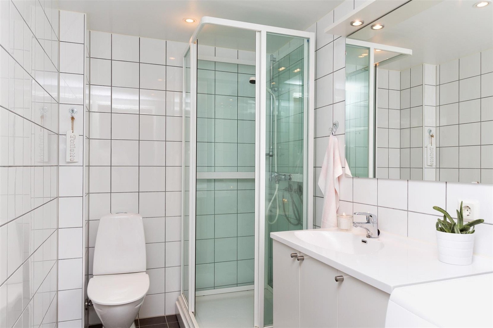 Flott bad innredet med dusjkabinet, wc, møbel og opplegg for vaskemaskin og kondenstørketrommel. Galleribilde