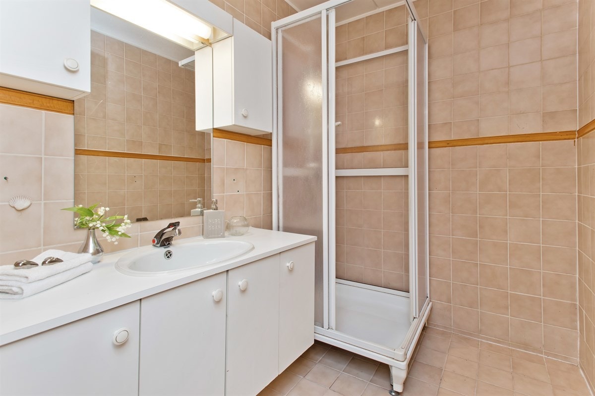 Flislagt bad med dusjkabinett og servant med skapinnredning Galleribilde