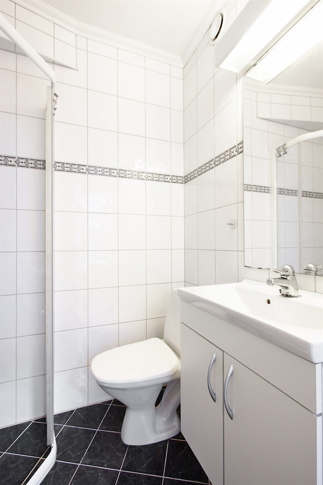 Badet har servant med tilhørende hvitprofilert innredning, dusjhjørne, klosett samt opplegg til vaskemaskin. Galleribilde