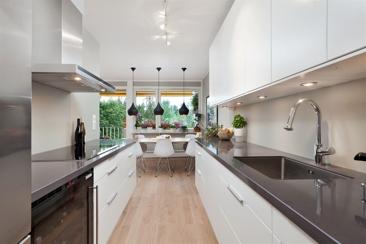 Kjøkken med plane fronter og integrerte hvitevarer mot spiseplass Galleribilde