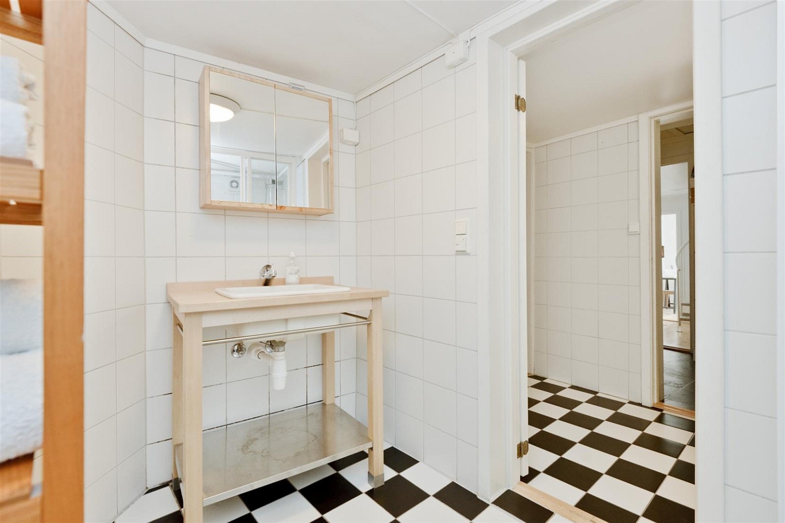 Lyse fliser på vegger og fliser i sjakkmønster på gulv, bidrar til å gi badet et luftig preg. Galleribilde