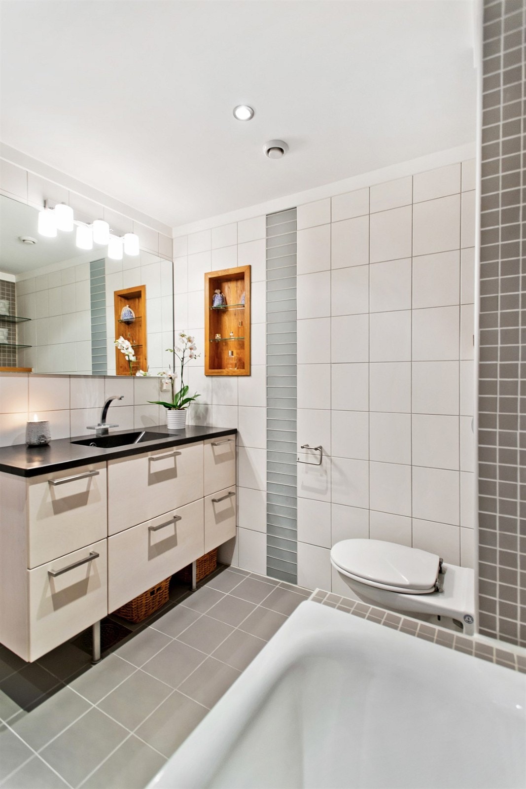 Innmurt badekar og vegghengt wc, samt rikelig med oppbevaringsplass Galleribilde