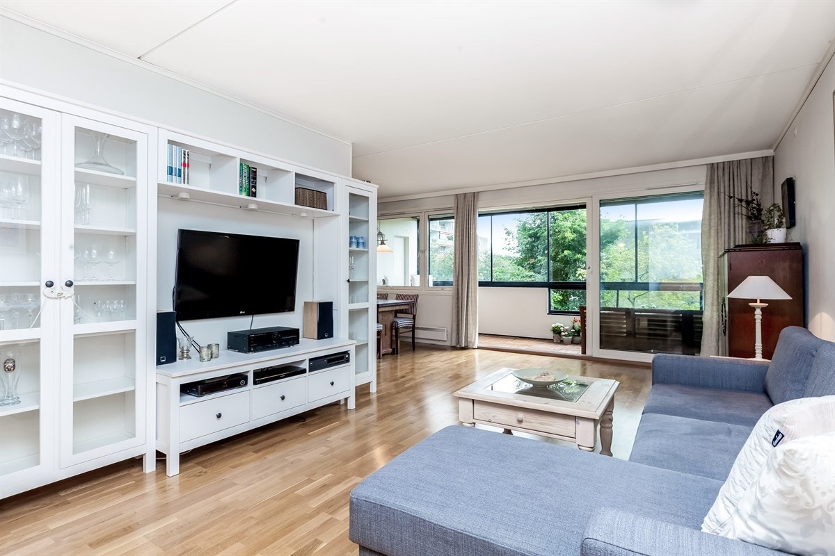 Romslig stue med parkettgulv og store lysflater Galleribilde