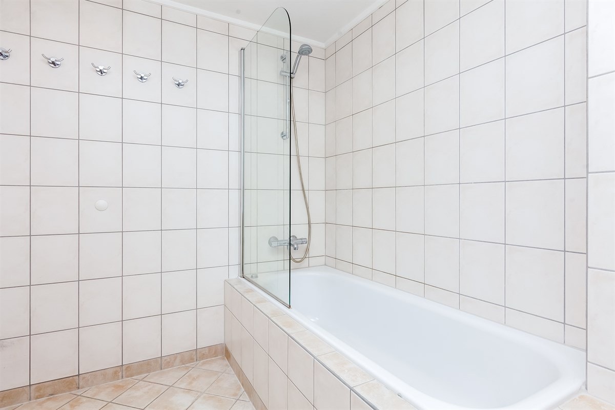 Innmurt badekar med dusjvegg, vegghengt wc og varmekabler Galleribilde