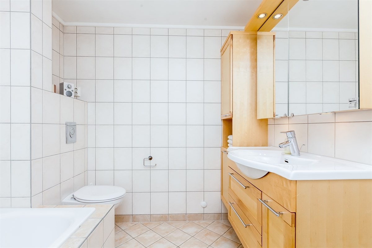 Pent flislagt bad med tidsriktige fliser og interiør med god oppbevaringsplass Galleribilde