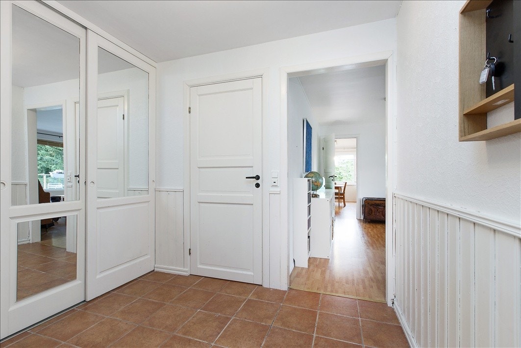 Stor entré/gang med skyvedørsgarderobe og fliser på gulv Galleribilde