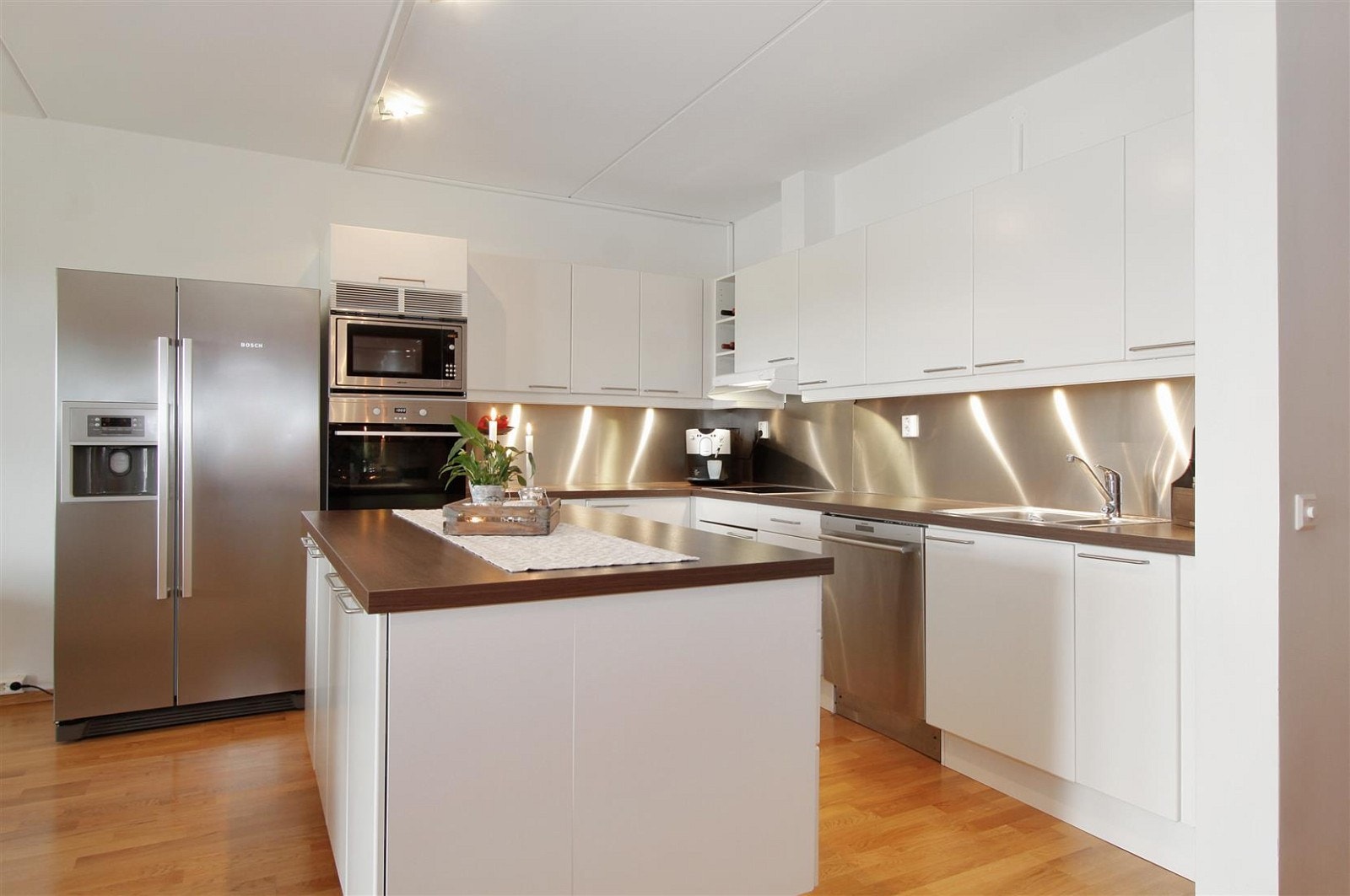 Pent kjøkken med mye skap- og benkeplass. Den store kjøkkenøyen har matskuffer mot kjøkkensiden og skap mot stuesiden Galleribilde