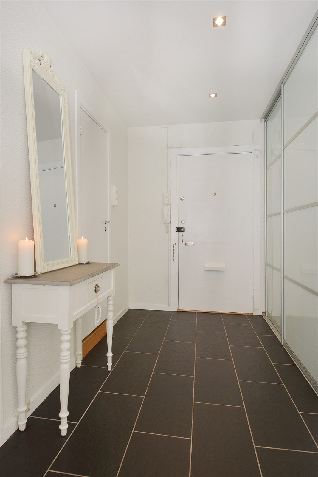 Entreen har skyvedørsgarderobe med frostede glassfronter, fliser på gulv, gulvvarme, downlights i himling og callinganlegg. Entreen er holdt i lyse, nøytrale farger, noe som er gjennomgående for resten av leiligheten. Galleribilde