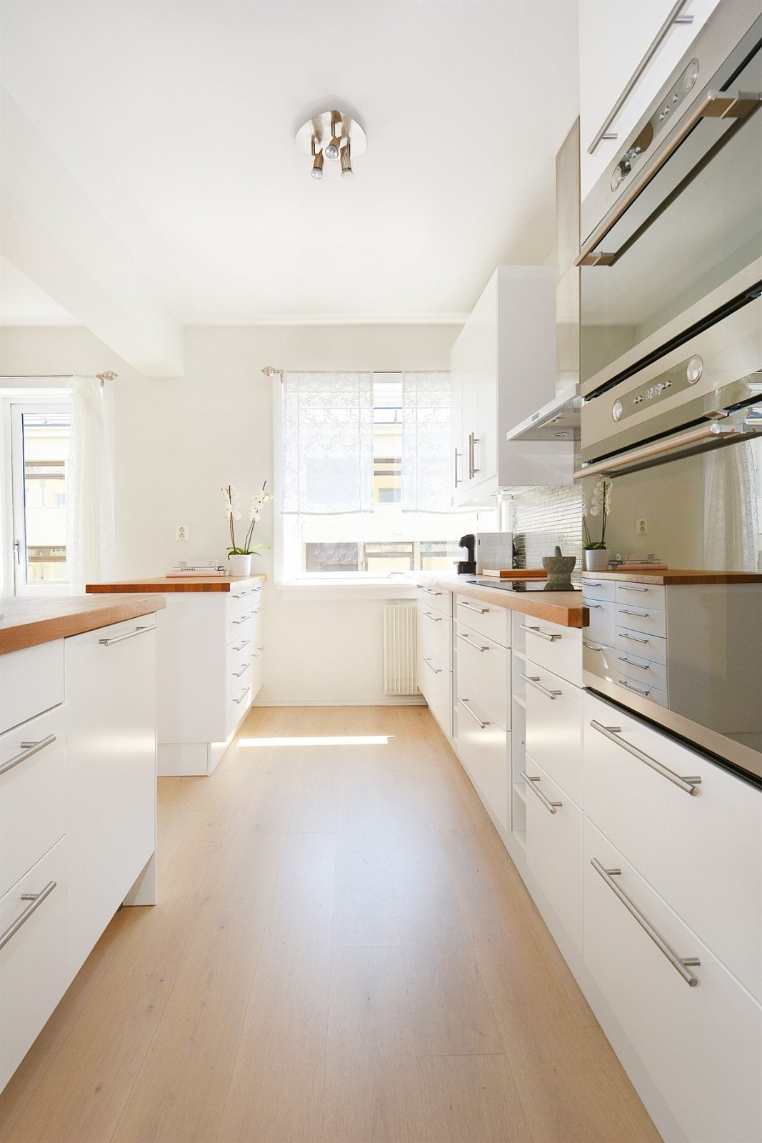 Innredningen har hvite, glatte fronter og heltre benkeplate i eik med enkel vaskekum og nedfelt induksjonstopp. Galleribilde