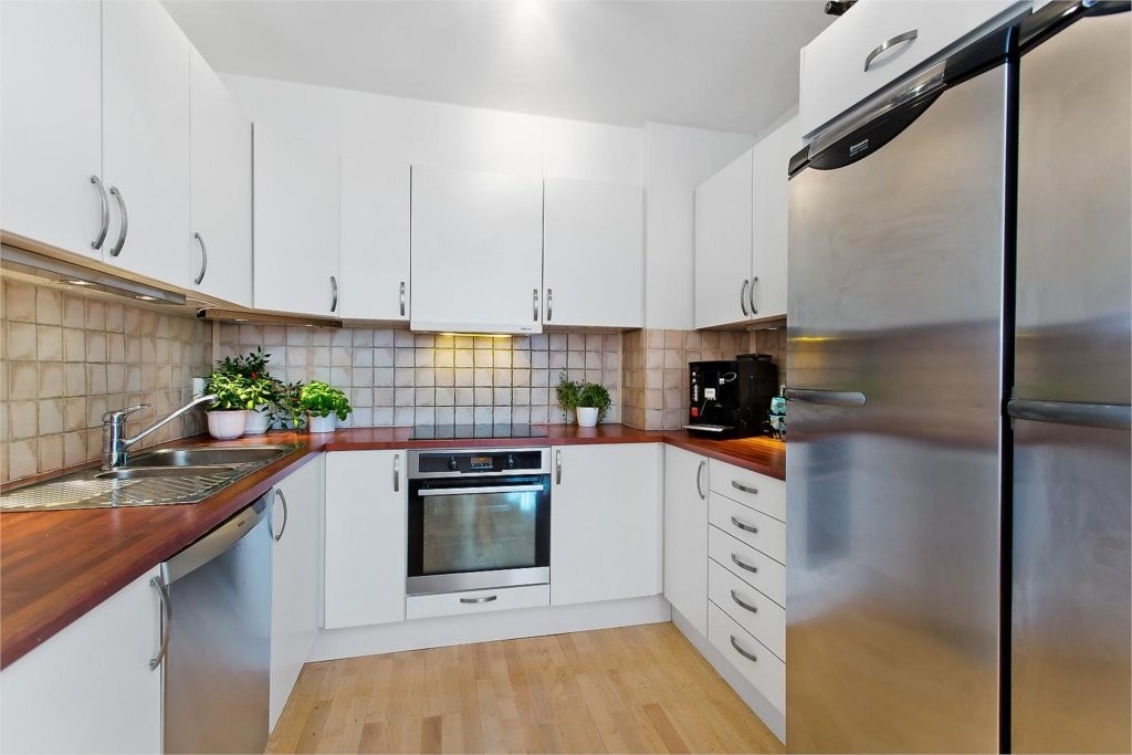 Stort og romslig kjøkken med innredning fra Sigdal. Fronter i hvit melamin. Integrert stekeovn samt induksjon platetopp. Varmtvannsbereder er montert i kjøkkenbenk. Delikate fliser mellom overskap og benkeplate. Det er montert brannslange på kjøkken. Galleribilde