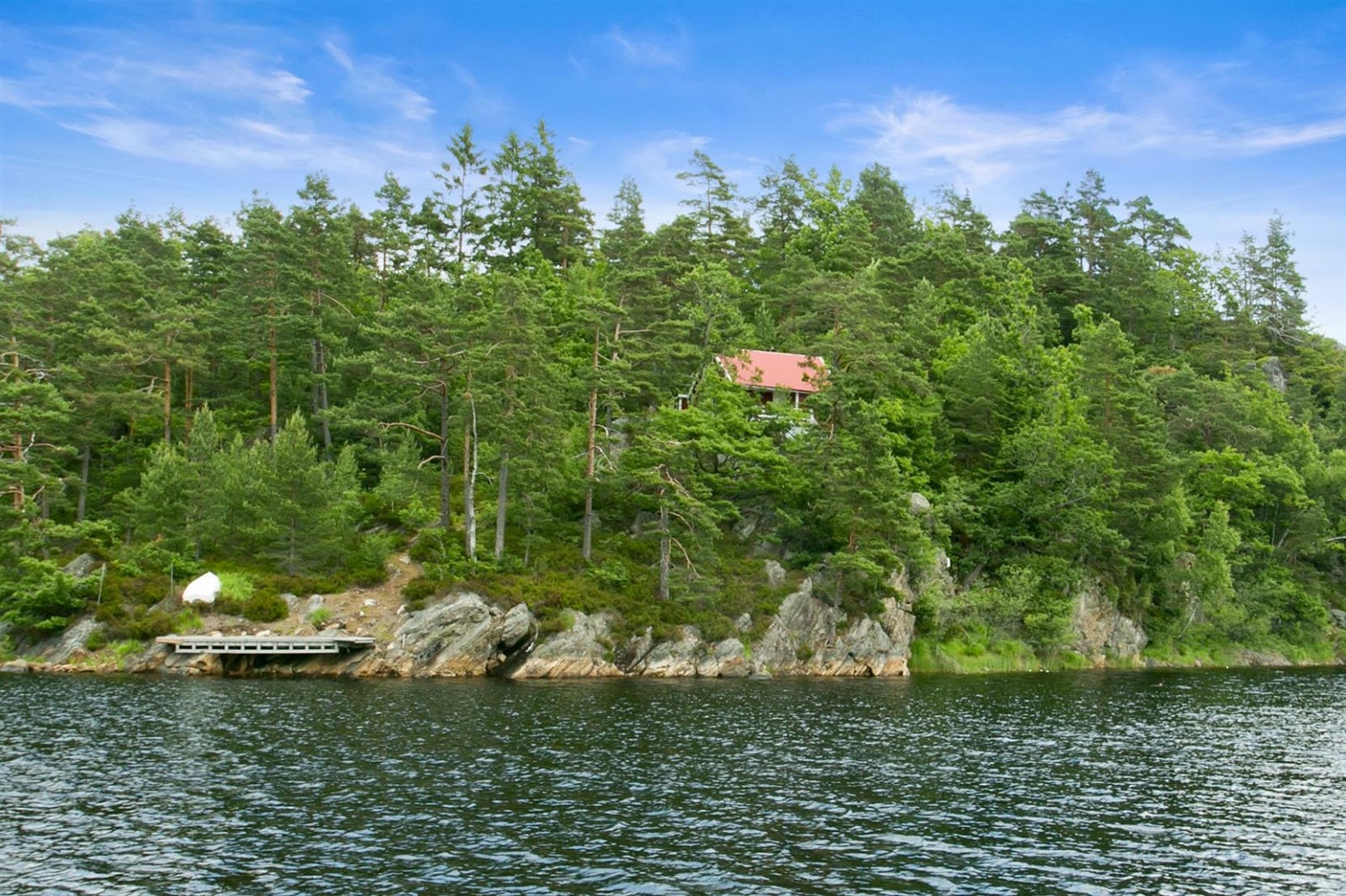 Hytta ligger godt i terrenget. Legg merke til brygga nede på venstre side. Galleribilde