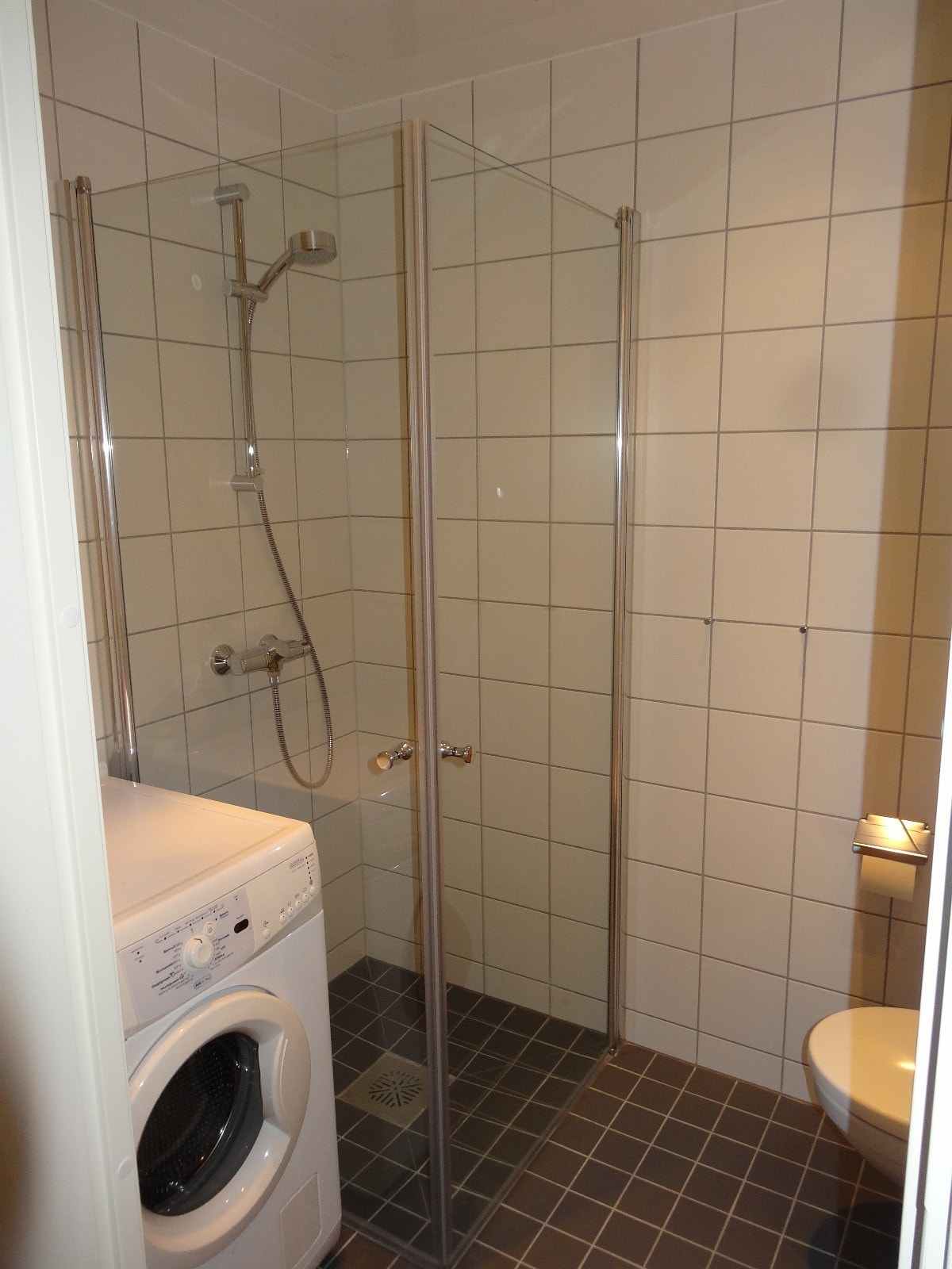 Flislagt bad med gulvvarme, dusj, vaskemaskin, og servant. Galleribilde