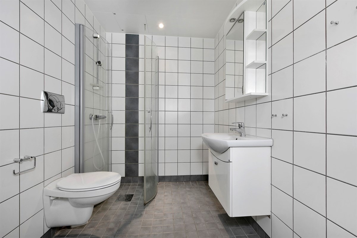 Boligen inneholder et delikat baderom. Badet er utstyrt med moderne fliser på og vegg, gulvvarme, downlights og heldekkende servant på servantmøblement. Galleribilde