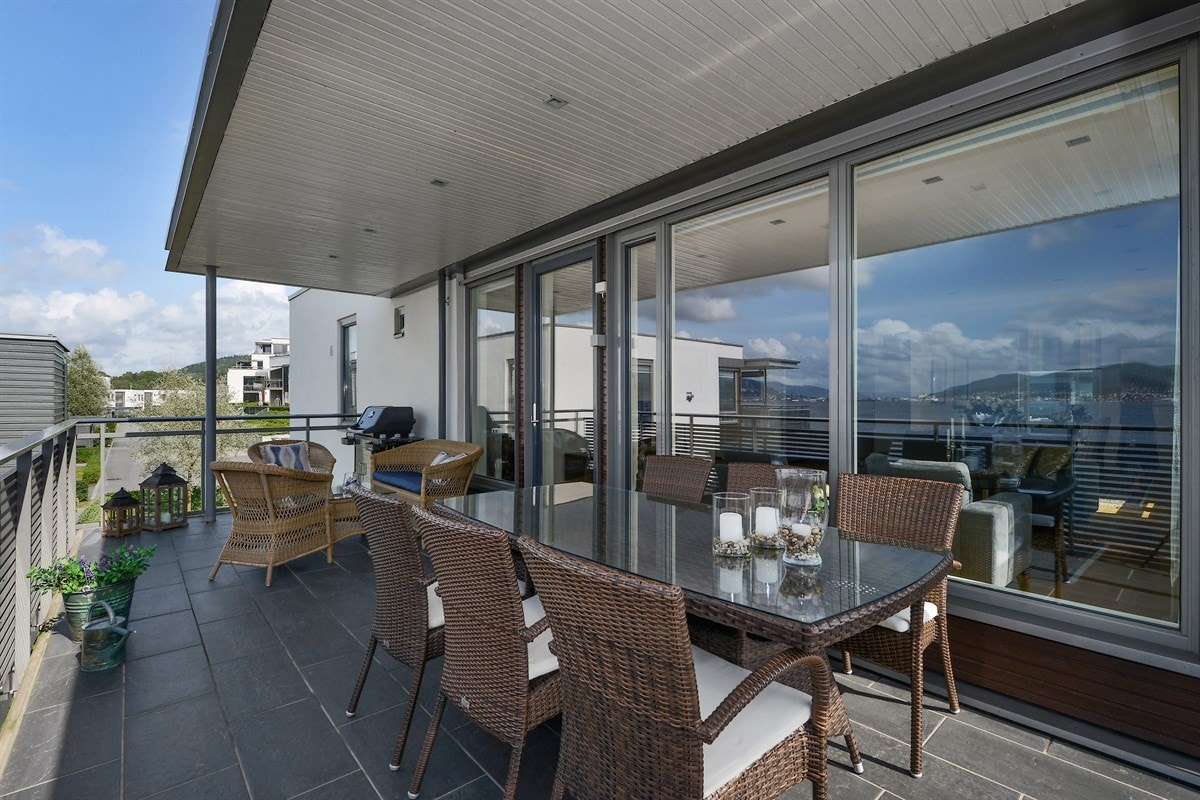 Terrassen er beskyttet av tak med innfelte downlights, keramiske fliser og gassuttak for grill. Galleribilde