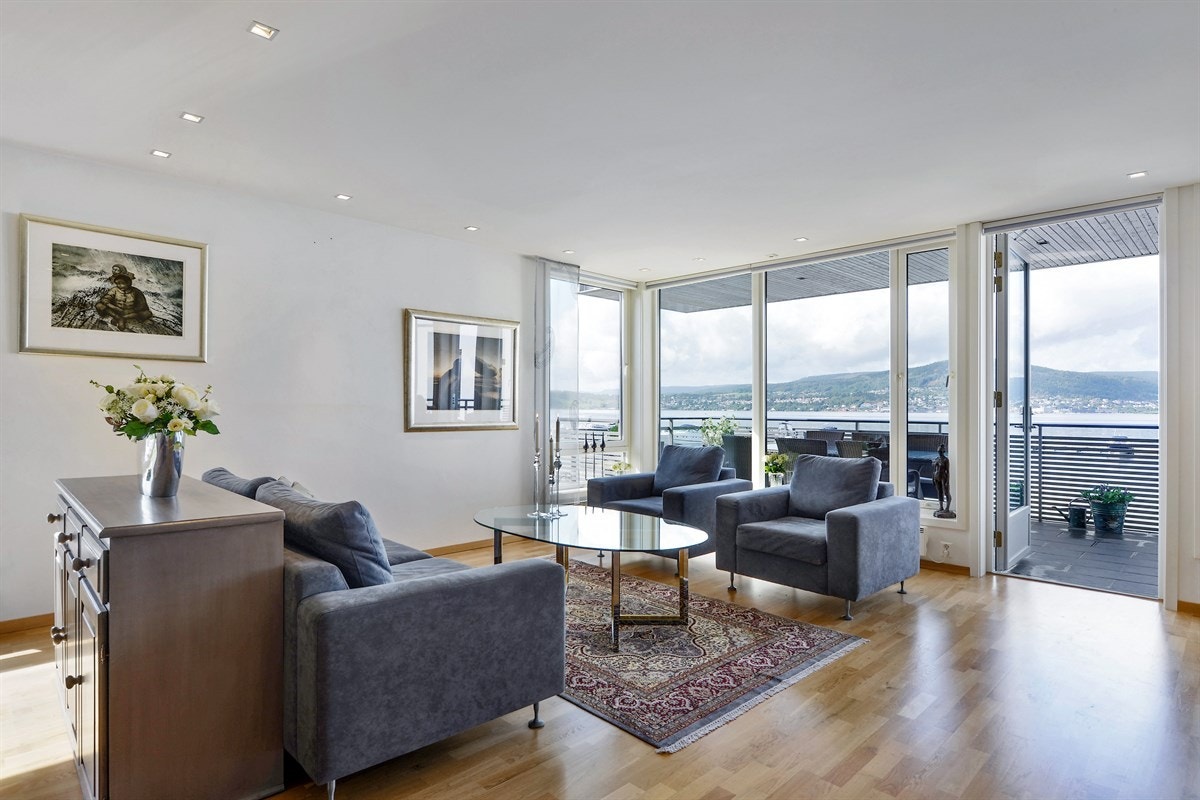 Flott lys stue med panoramautsikt mot fjorden og bryggen. Store vinduspartier gir en meget god romfølelse. Innvendige persienner i stuen. Galleribilde