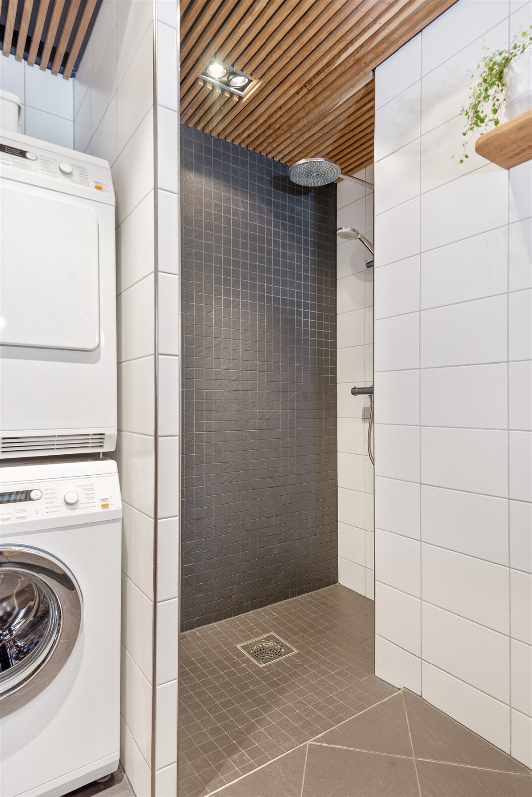 Bad med dusjnisje og opplegg for vaskemaskin og tørketrommel. Galleribilde