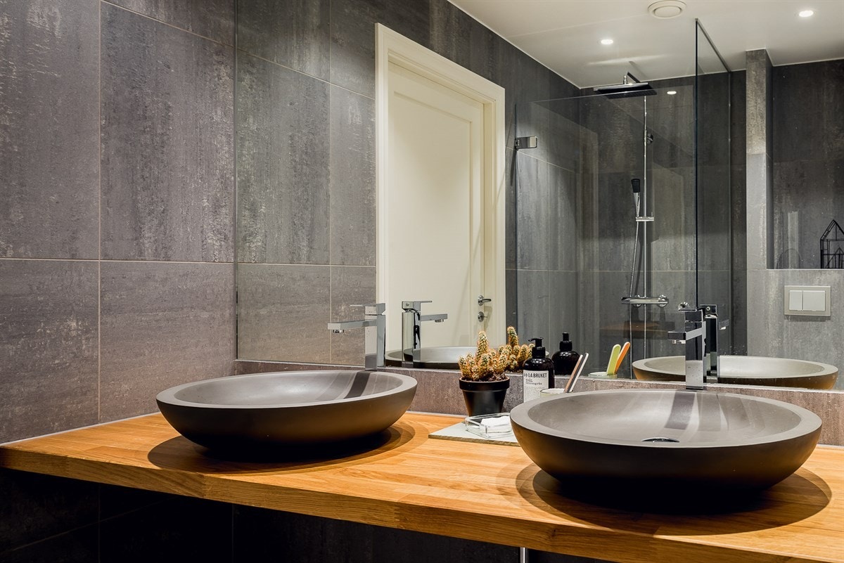 Det kanskje mest fremtredende elementet på badet er en høy og vid speilflate som dekker hele veggen, samt at dobbel servant åpner for samtidig bruk av badet. Galleribilde