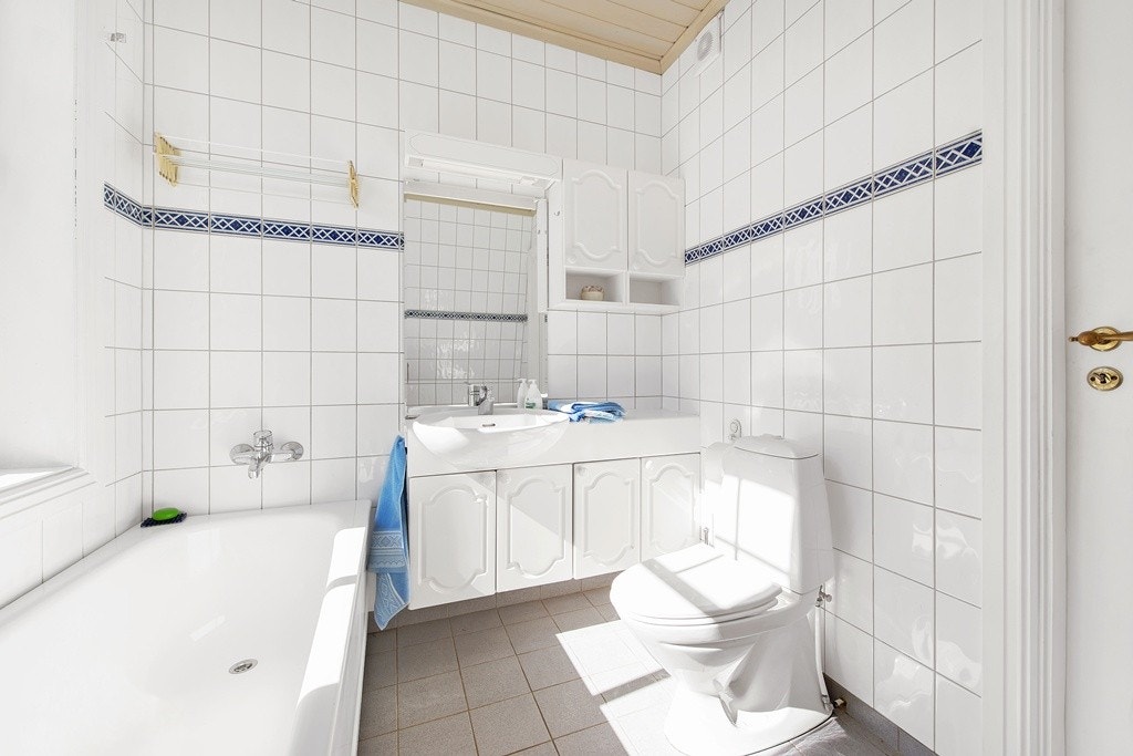 Badet er innredd med lyse fliser og lys innredning med masse lagringsplass. Galleribilde