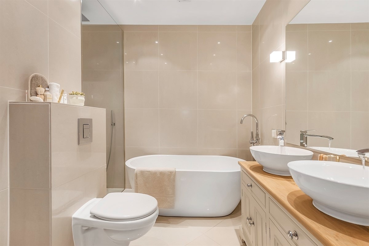 Boligen inneholder to eksklusive baderom med lekre detaljer og løsninger. Begge badene har fliser på vegg og gulv, gulvvarme, downlights, veggmontert toalett og deilig regnfallsdusj fra taket Galleribilde