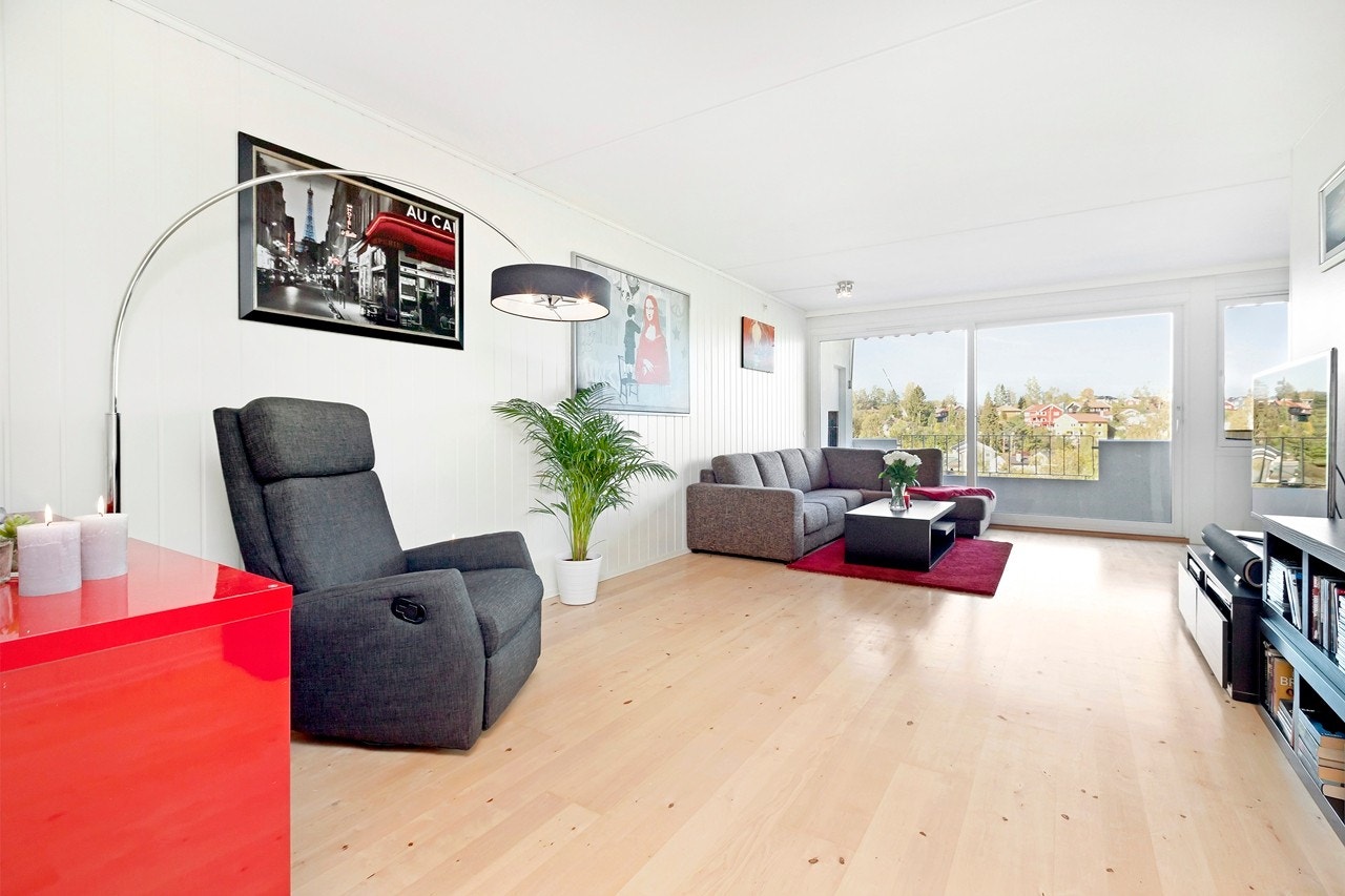 Pen stue med store vindusflater ut mot balkong som slipper inn mye lys. Galleribilde