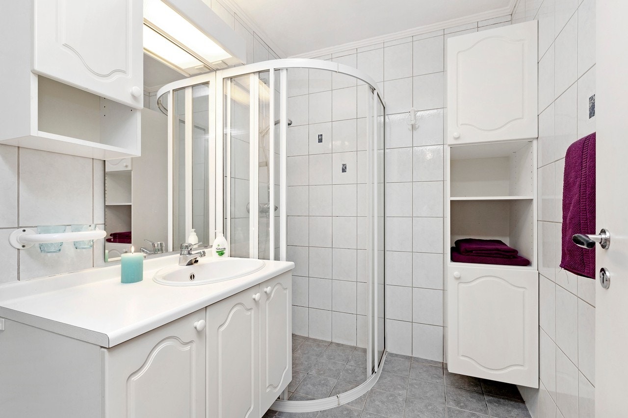 Flislagt baderom med dusjhjørne og servant med underskap. Nye gulvfliser ble lagt i 2012 i forbindelse med innstallering av varmekabler. Galleribilde