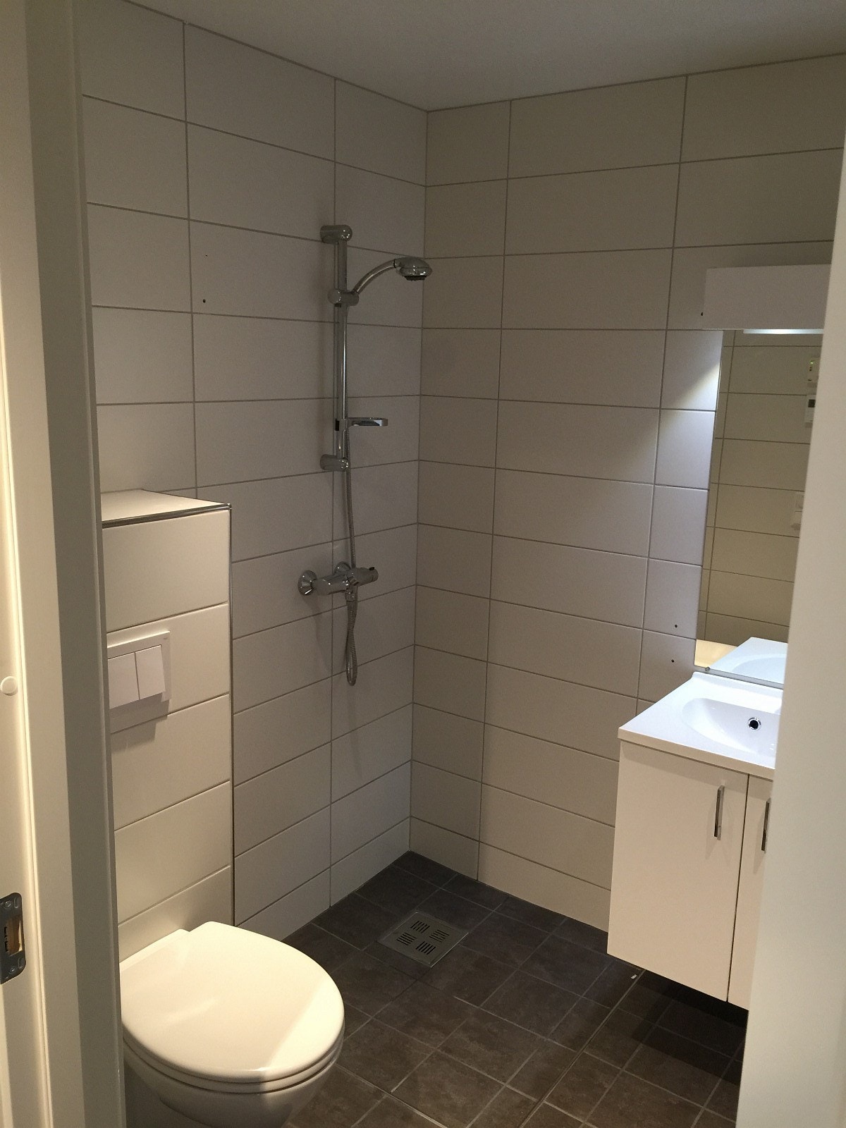 Bad med dusjdører og vegghengt toalett Galleribilde