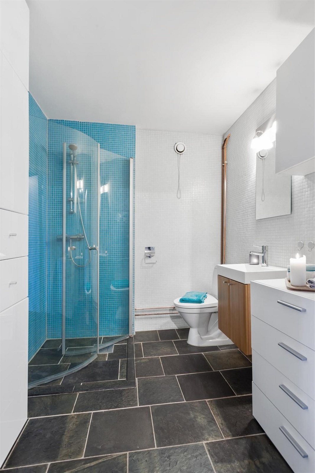 Pent bad med dusjhjrne, WC, speil med belysning over servant med underskap. Galleribilde