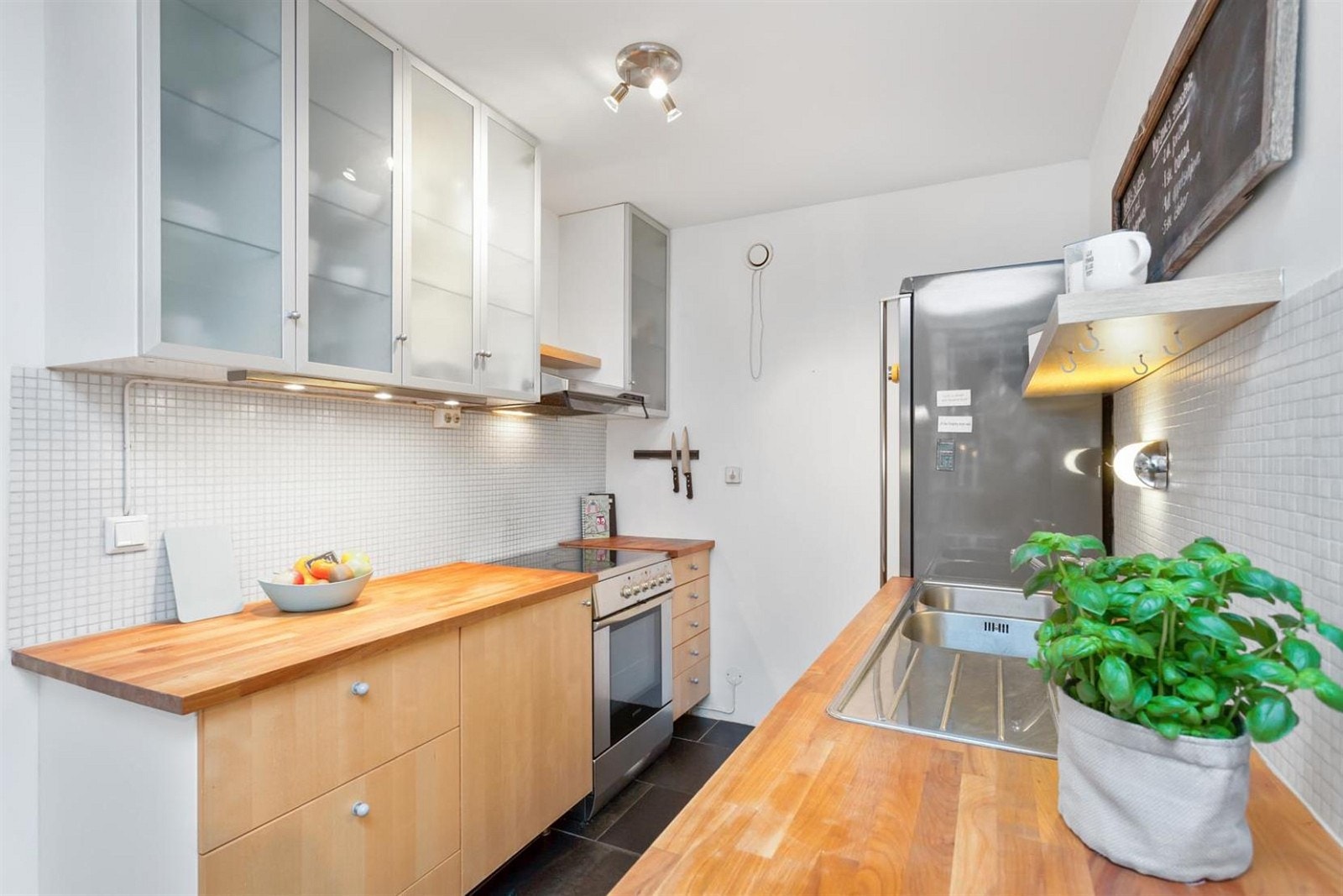 Godt med oppbevaring i vegg- og benkeskap, mosaikkfliser over heltre benkeplater. Galleribilde